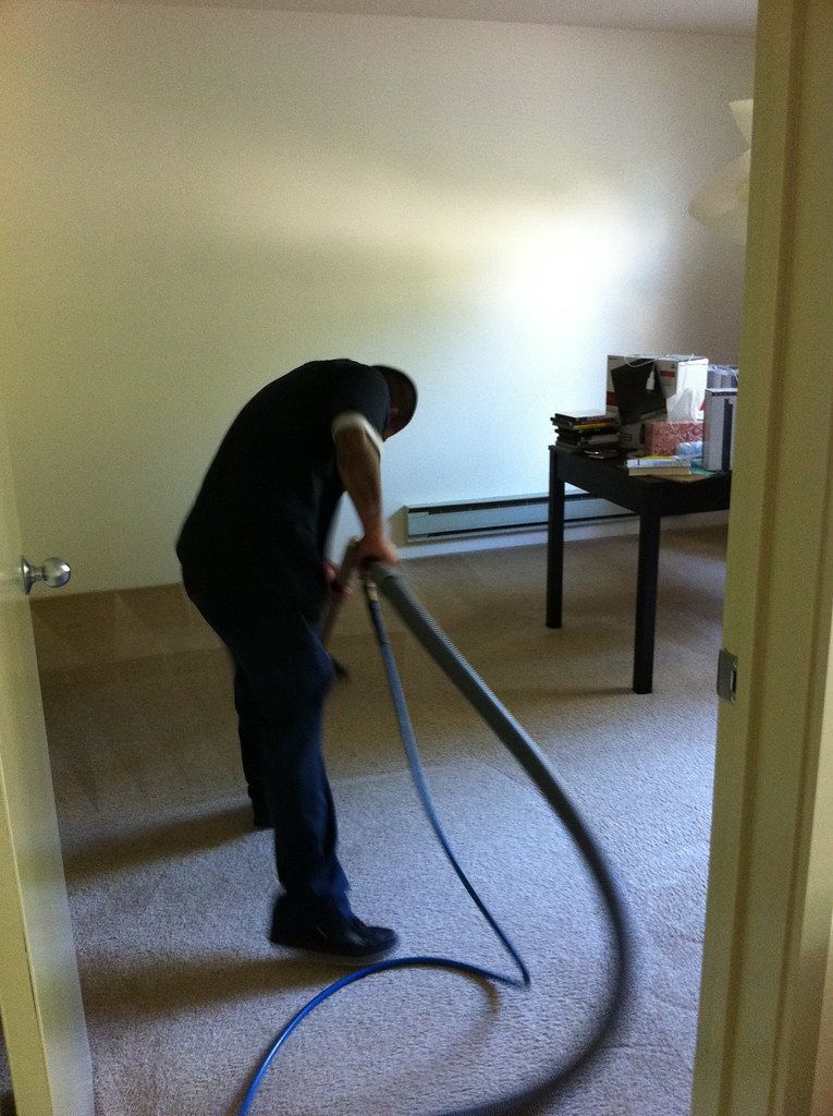 A Maxclean technician cleaning carpet with a wand
